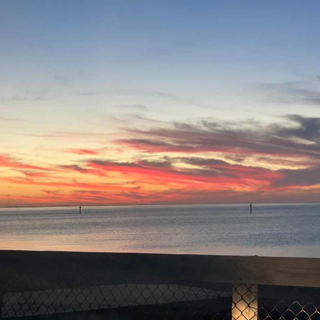 Beautiful pink and purple sunset sky seen over ocean water with dramatic clouds, quiet evening