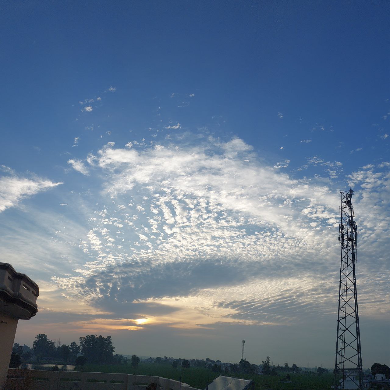 Bright blue sky filled with fluffy white clouds and a tall tower, clear day