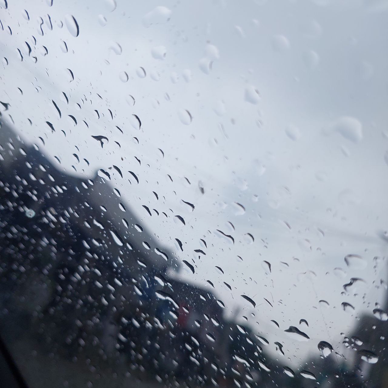 Close-up of Rain Drops on Car Window with blurred city view, rainy day photography